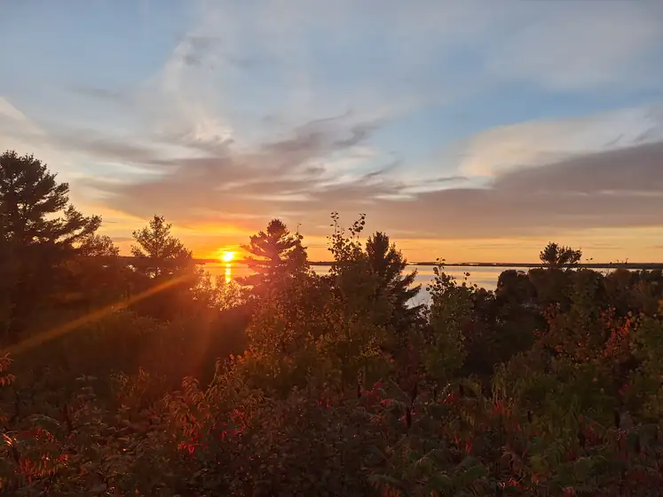 Sun setting through pines over a lake